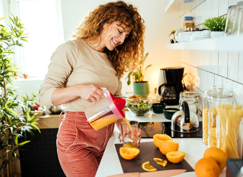 kobieta przygotowująca świeżo wyciskane soki owocowe