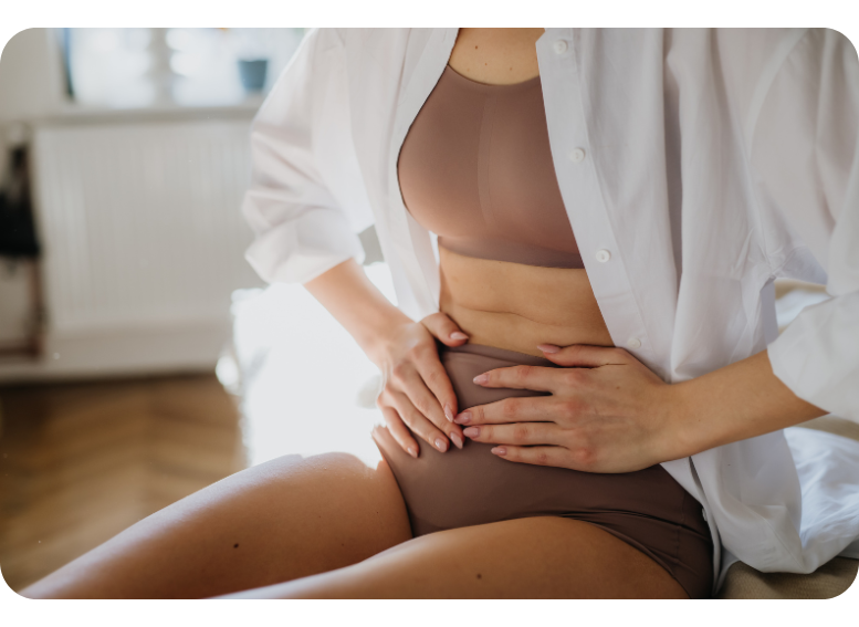 Kobieta odczuwająca ból brzucha związany z endometriozą, jednym z głównych objawów tej przewlekłej choroby zapalnej, która może prowadzić do silnych dolegliwości menstruacyjnych i bólu miednicy.